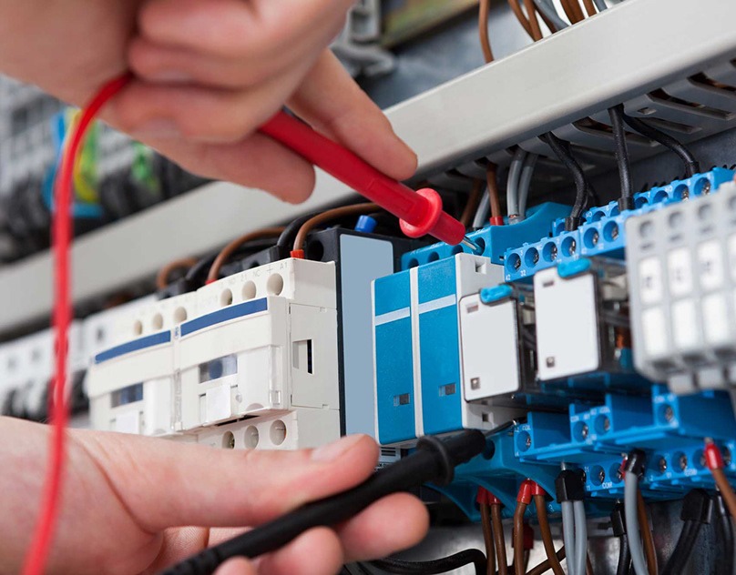 Engenheiro elétrico realizando manutenção em um sistema de comandos elétricos